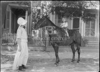 Young girl standing by boy on horse