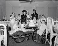 Shriner, woman and cake with children in hospital; Loew's Theater