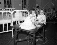 Shriner, woman and cake with children in hospital; Loew's Theater