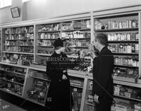 Mading's Drugstore clerk with customer, no. 1941; Pharmacy