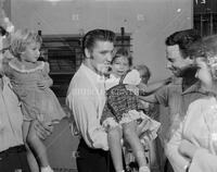 Photograph of Elvis Presley holding child and meeting fans