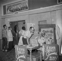 Photograph of Colonel Tom Parker selling Elvis Presley souvenirs in theater lobby
