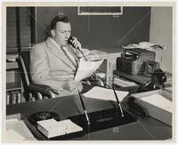 Athelstan Spilhaus speaking on the telephone in an office