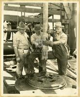 [Three men operating oil drill]