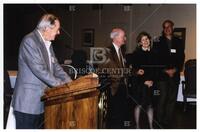 Bernard Rapoport at podium with Wales Madden, Kay Bailey Hutchison, and William Cunningham at University of Texas at Austin event