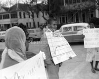 Man holding chart, protesters with signs - Integration Protest