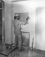 Man installing plaque inside new Drama Building