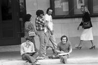 Photograph of architecture students drawing with people looking at them