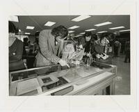 Photograph of people with drinks looking at books in a case