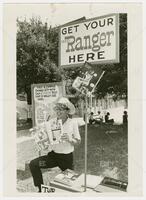 Photograph of UT student with stack of Texas Ranger magazines and sign