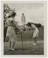 Photograph of two ladies golfing with the UT Tower in the background.