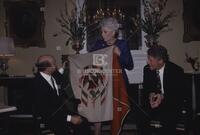 Photograph of Ann Richards holding up a flag in front of Carlos Salinas de Gortari and Bill Clinton, 1993