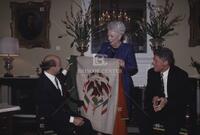 Photograph of Ann Richards holding up a flag in front of Carlos Salinas de Gortari and Bill Clinton, 1993