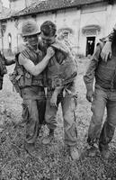 Photograph of a U.S. Marine helping a wounded Marine out of a church in Vietnam, 1967