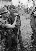 Photograph of a U.S. Marine helping a wounded Marine out of a church in Vietnam, 1967