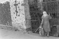 Photograph of a person in front of a destroyed church