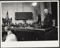 Black and white photograph of Jack Brooks, standing with hands in pockets, during the Iran-Contra trials, 1987
