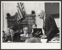 Black and white photograph of Jack Brooks leaning over a microphone during the Iran-Contra trials, 1987