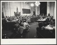 Black and white photo of the press sitting to take pictures during the Iran-Contra trials, 1987