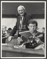 Black and white photograph of Jack Brooks standing and smiling at the camera during the Iran-Contra trials, 1987