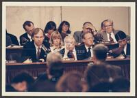 Color photograph of representatives looking stoic during the Iran-Contra trials, July 1987