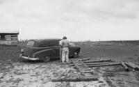 Two men talk outside of automobile