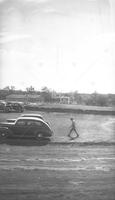 Photograph of Four Cars and One Person in Front of a Building Under Construction