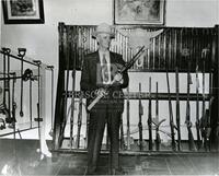 [Roy W. Aldrich holding a rifle inside Sul Ross Museum]