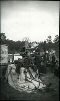 [Men standing next to saddle and other artifacts of the Old West]